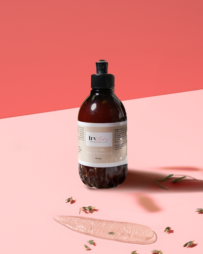 Goat’s Kiss Shower and Bath Gel bottle with creamy gel on pink surface and coral background