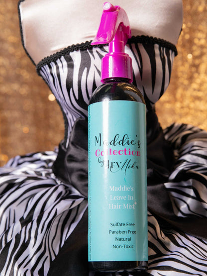 Maddie’s Leave-In Hair Mist bottle with pink spray nozzle on zebra-striped fabric background